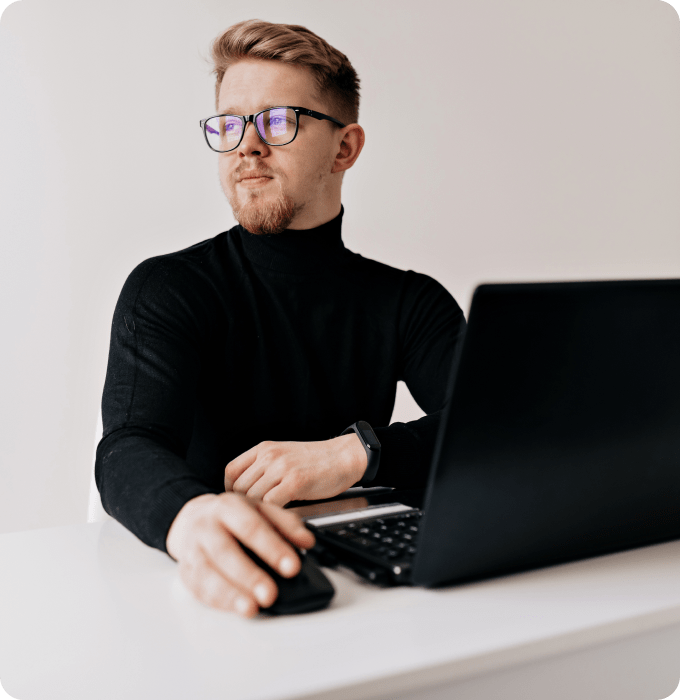 a man with glasses sits next to a laptop